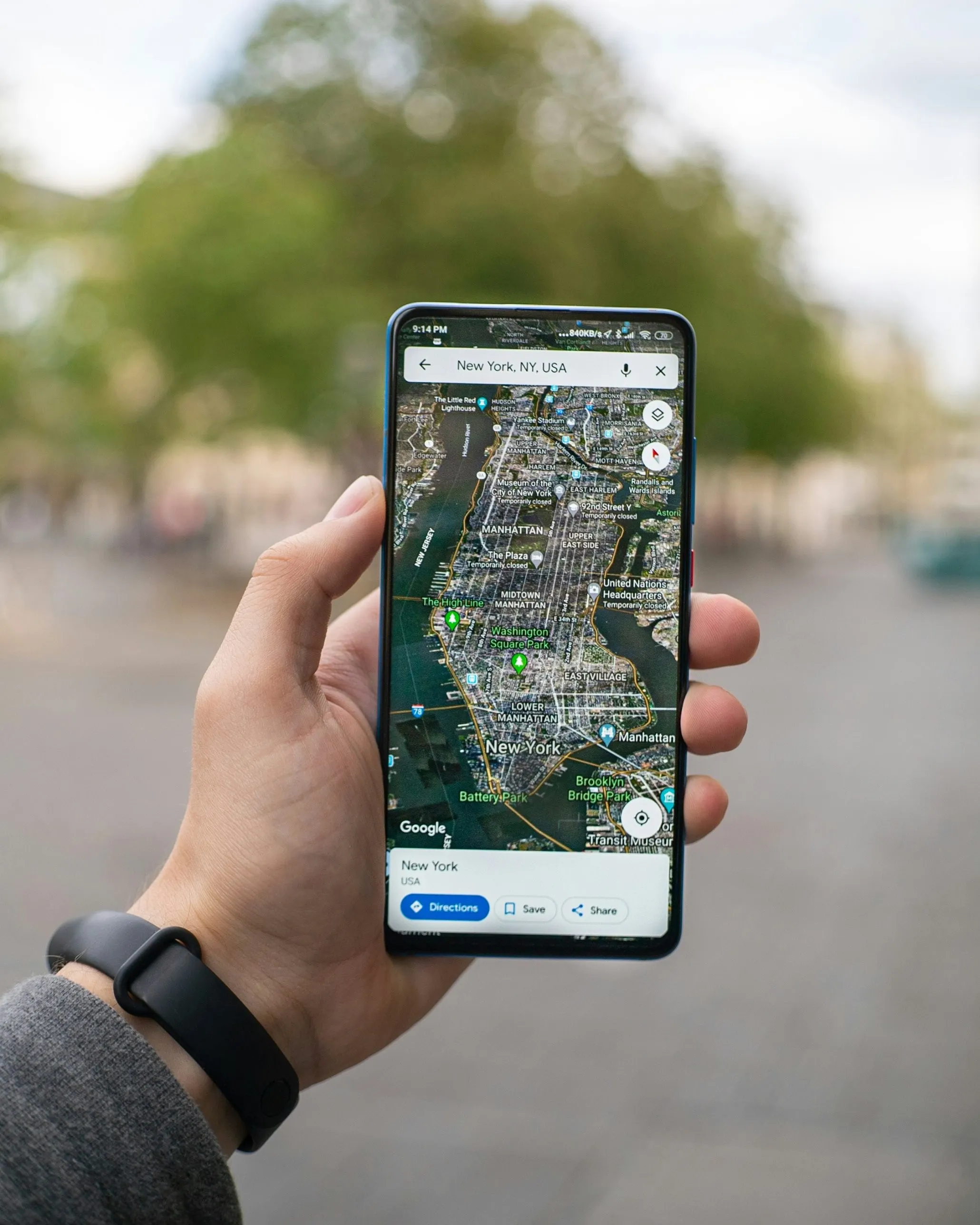 Ruka drží telefon s otevřenou mapou Google